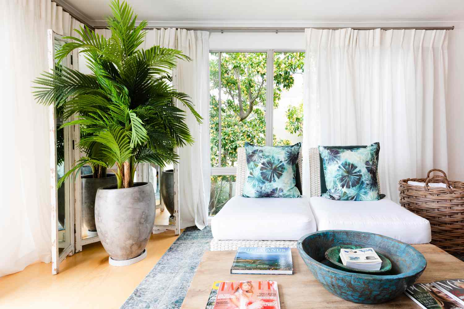 Beach house living room with white lounge chairs and large potted palm