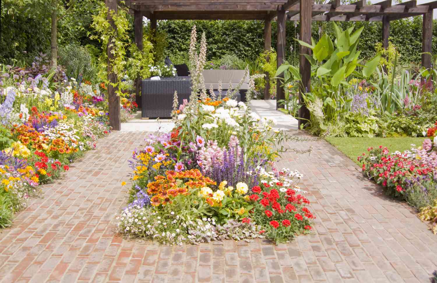 Patio de ladrillo con flores y pérgola.