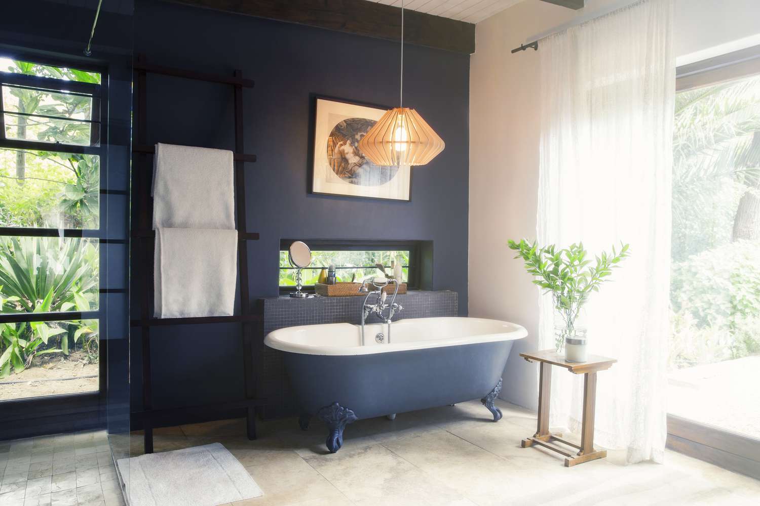 Ein dunkelblaues Badezimmer mit Badewanne und Handtuchhalter mit Blick auf einen schönen Hinterhof
