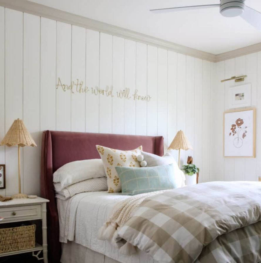 Chambre d'adolescente avec murs lambrissés blancs et lit double avec tête de lit rouge vin.