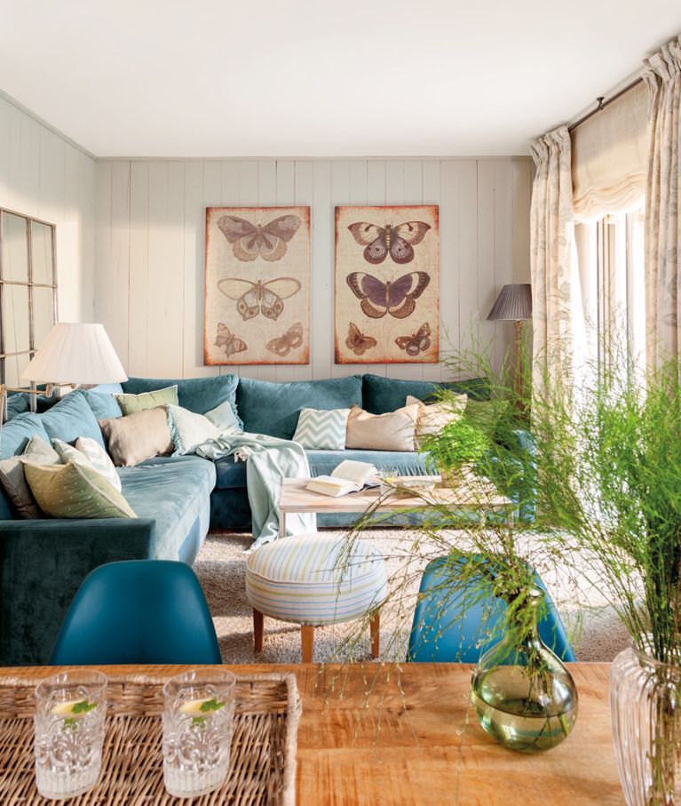 Salon beige confortable avec canapé et chaises turquoise, avec des imprimés de papillons sur le mur
