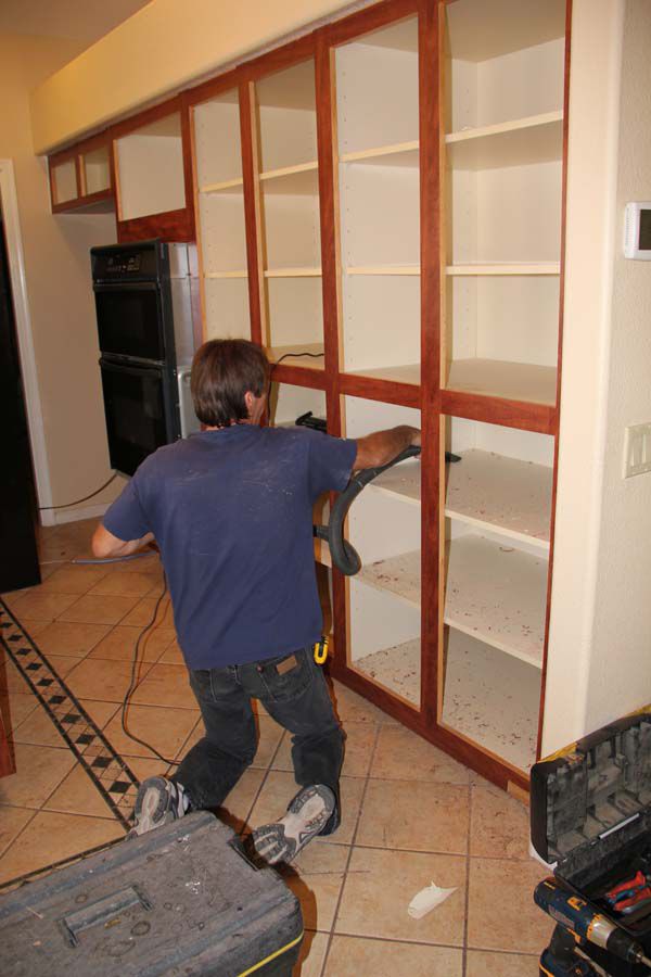 Hombre limpiando el interior de los armarios de la cocina