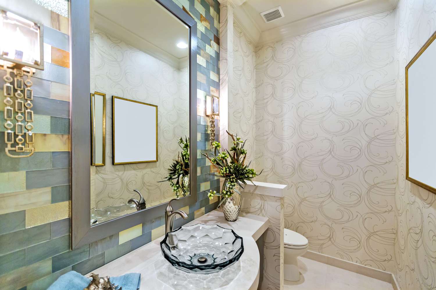 Ein Badezimmer mit bunten Glasfliesen, die das Waschbecken umgeben, und einer durch eine kleine Wand abgetrennten Toilette.
