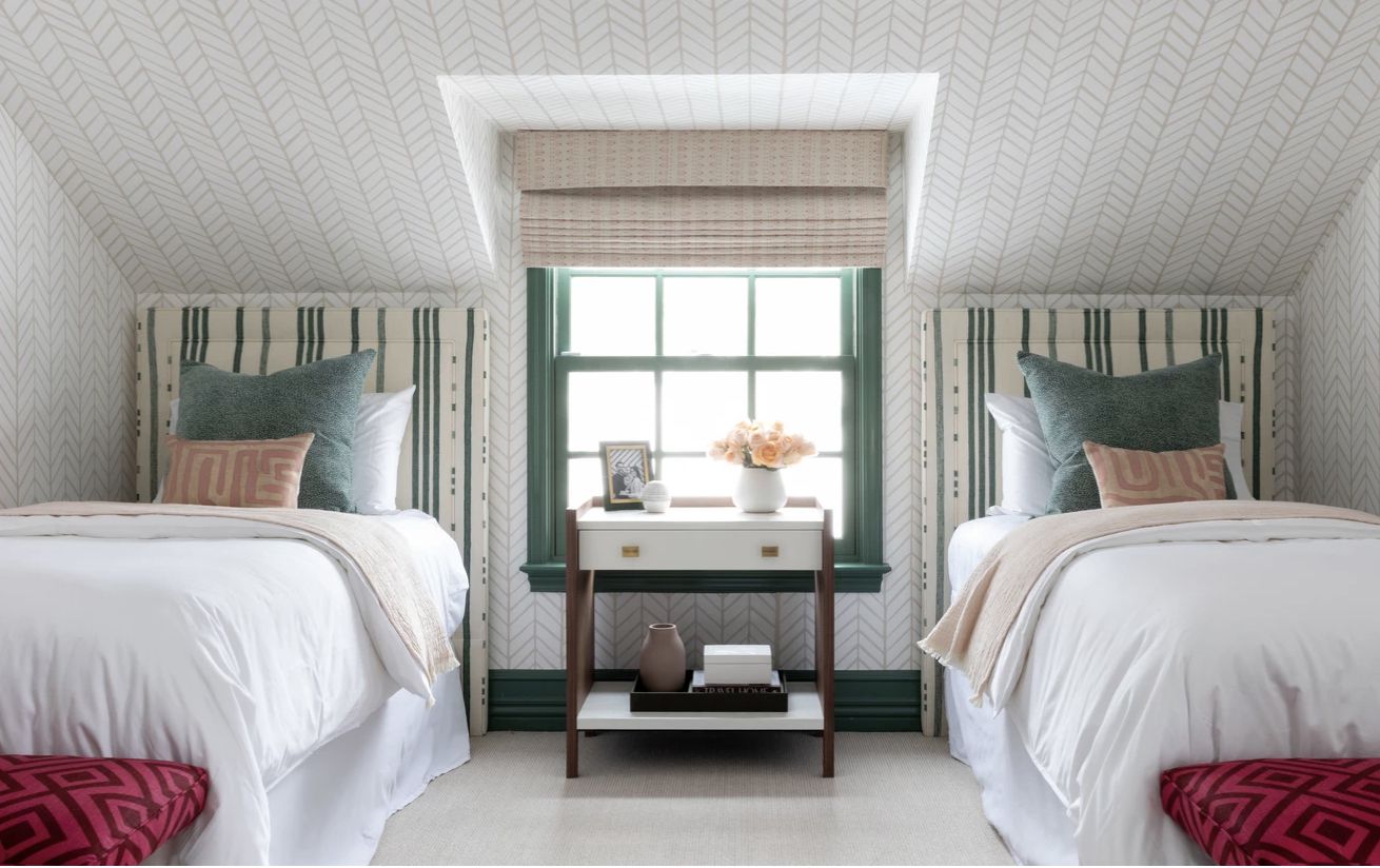 chambre à coucher avec principalement des couleurs vertes et blanches, poufs rouges au bout de chaque lit