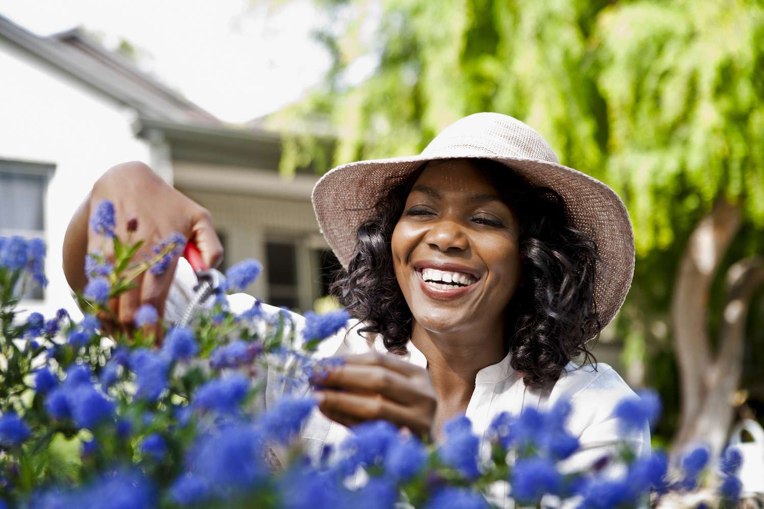 Mujer sonriente podando flores en el jardín