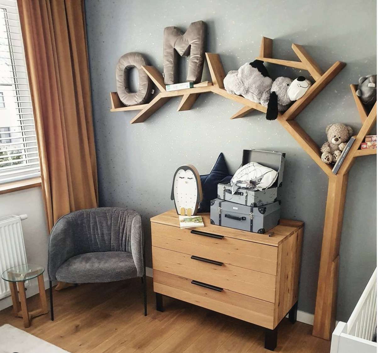 quarto de bebê cinza com móveis de madeira e prateleira de árvore