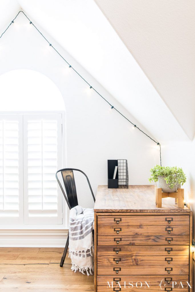 Uma grande sala branca com um suporte de madeira para plantas em uma mesa.