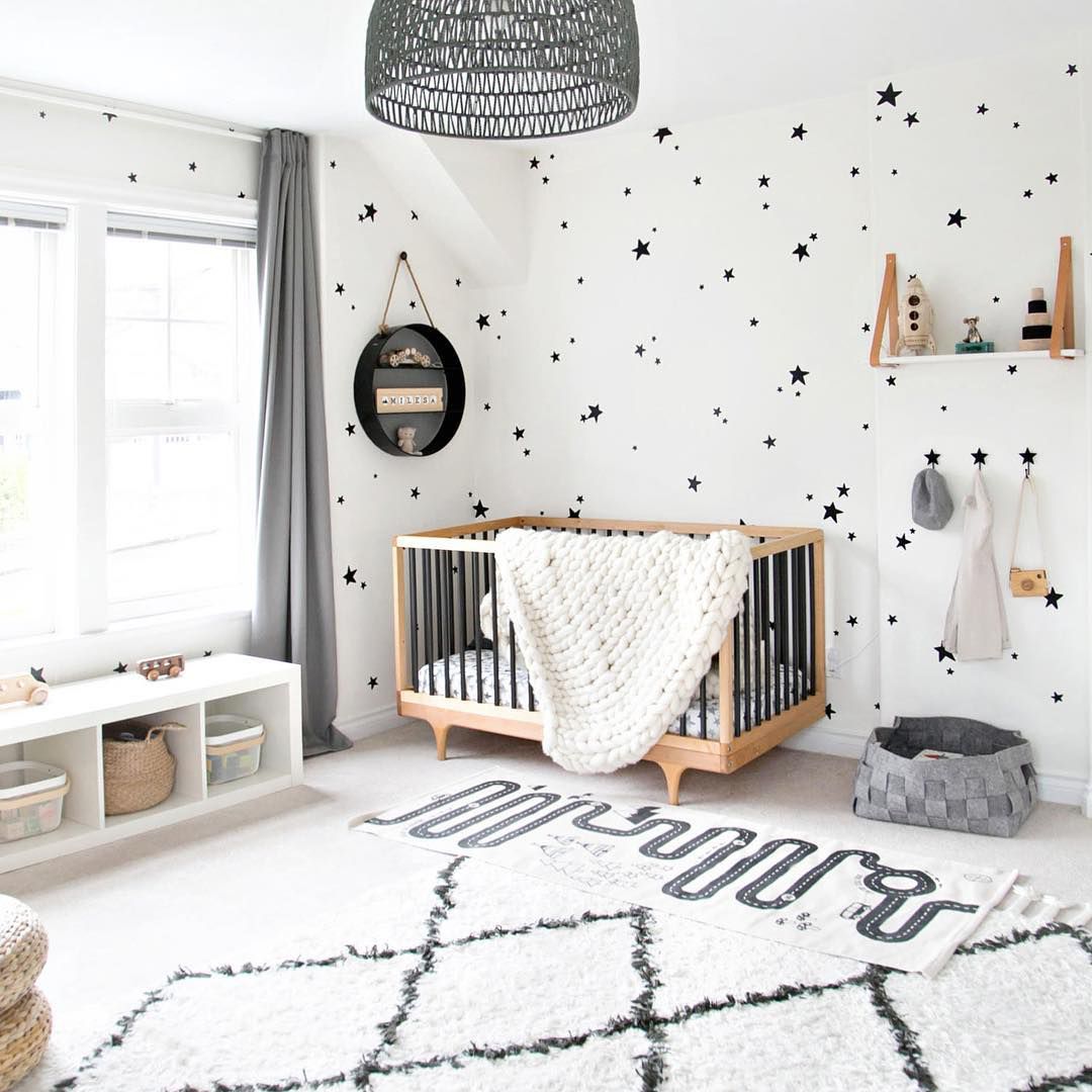 Quarto de bebê preto e branco com papel de parede com estampa gráfica de estrelas