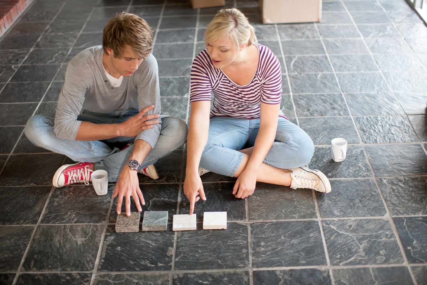 Jovem casal sentado no chão escolhendo novos azulejos