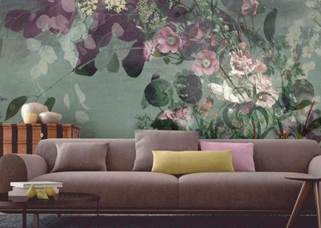 Purple couch in front of large floral print wall.