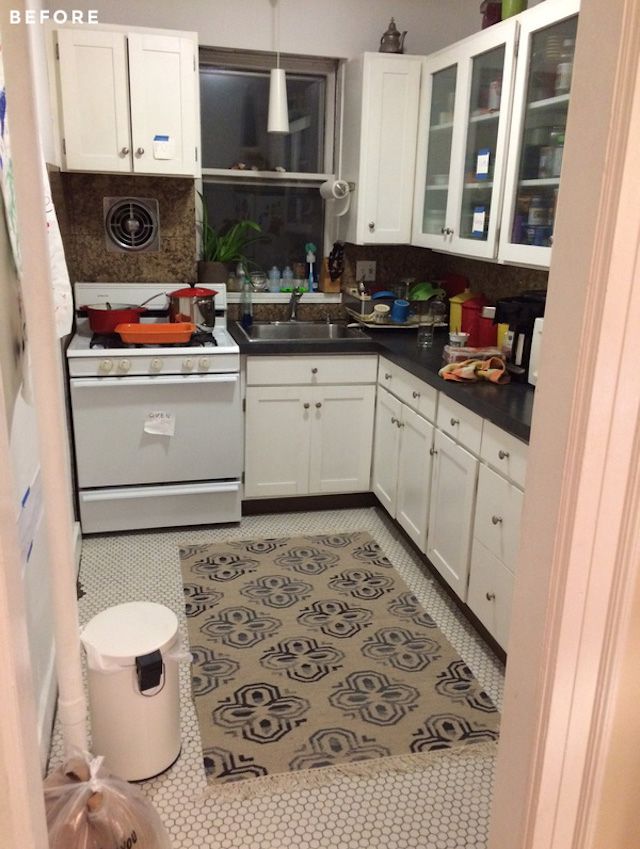 Cozinha branca com tapete e o espaço é apertado e desordenado.