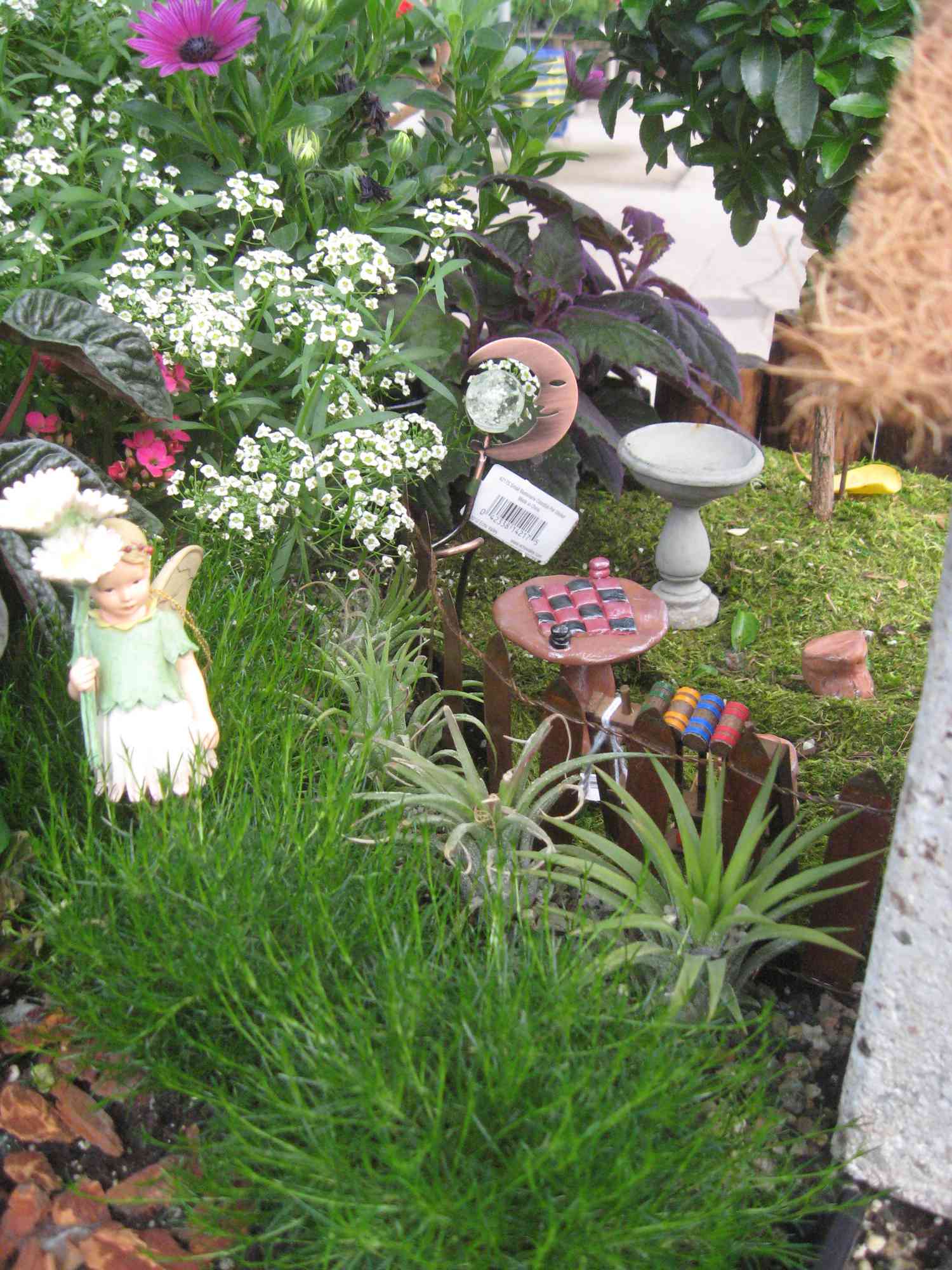 Móveis em miniatura e estátua de fada no jardim.