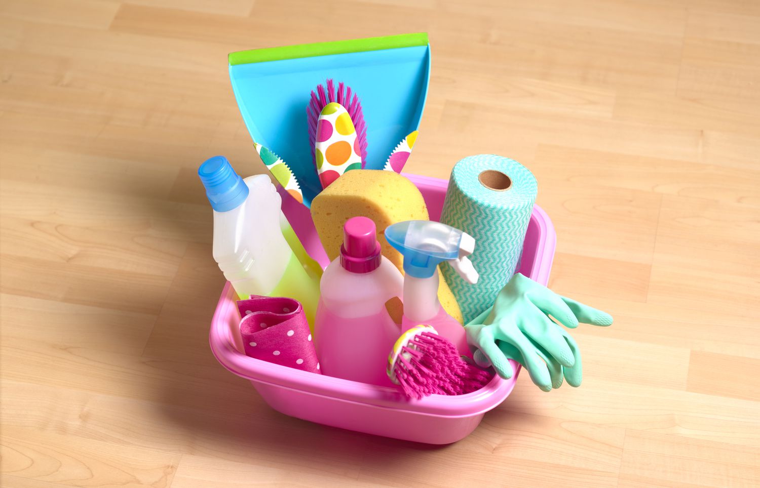 Ein pinkfarbener Duschkorb gefüllt mit Reinigungsmitteln.