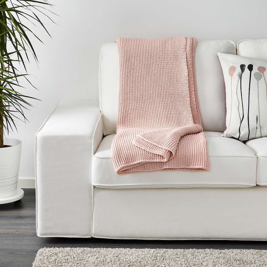 weiße Couch mit leichtem rosa Überwurf drapiert