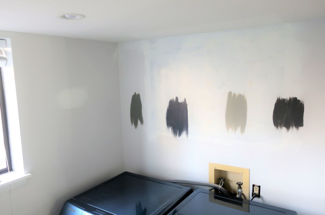 Lavadero desnudo con muestras de pintura en las paredes.