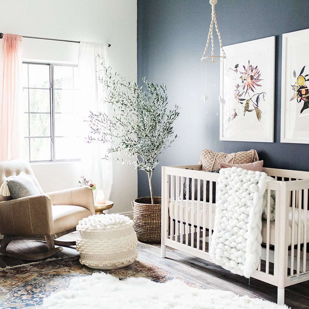 Neutral nursery with muted navy accent wall.