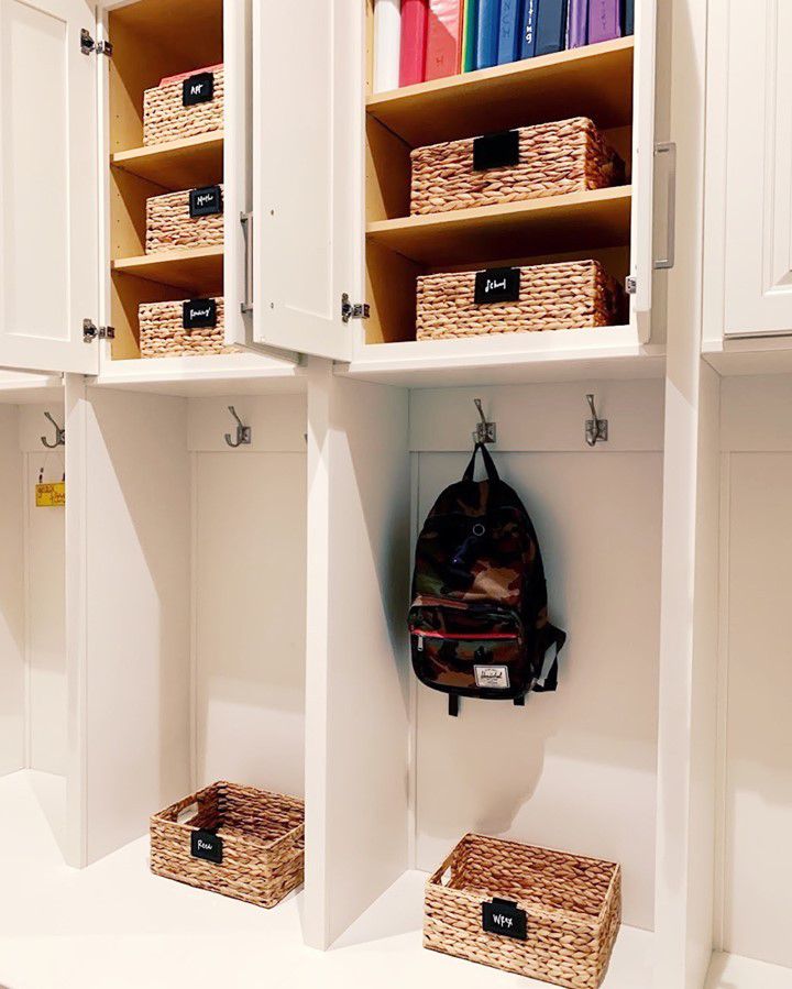 Un mudroom con armarios, cestas de almacenaje etiquetadas, ganchos y cubículos.