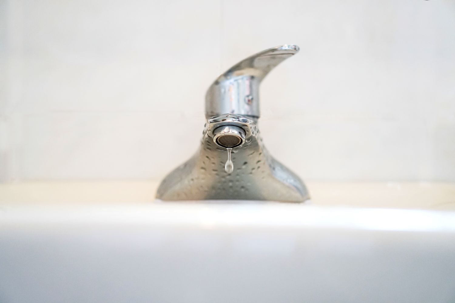 Primer plano de agua goteando del grifo en el lavabo del baño