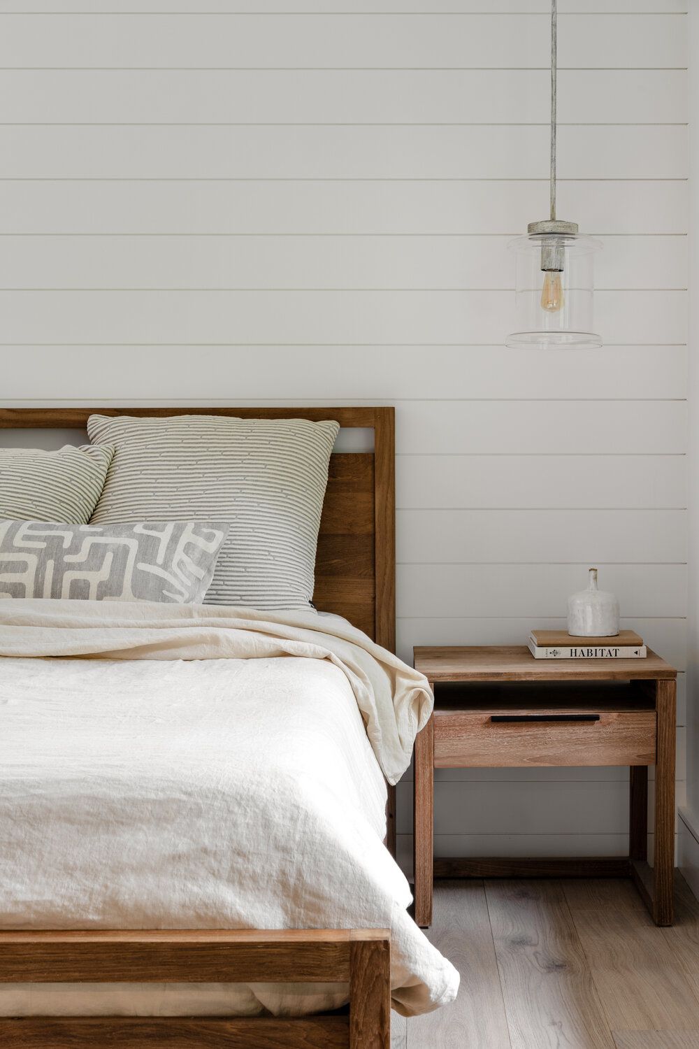 quarto neutro com paredes brancas shiplap e estrutura de madeira para cama/mesa de cabeceira