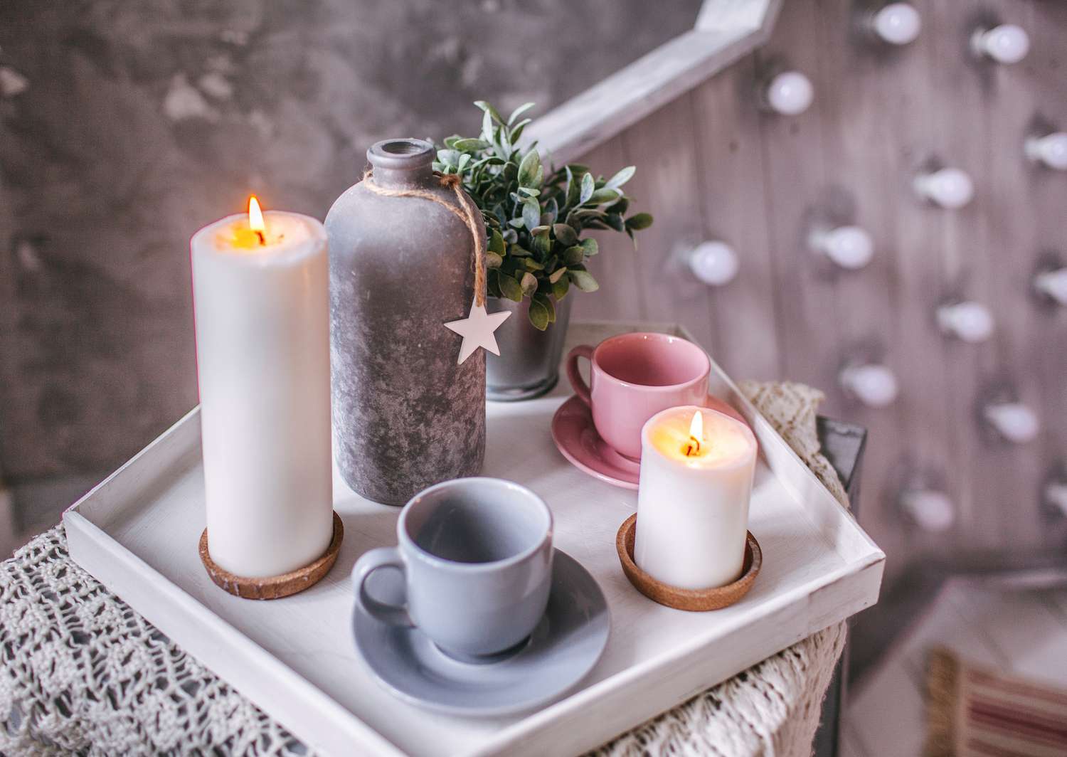 velas e xícaras de chá com uma planta em uma mesa