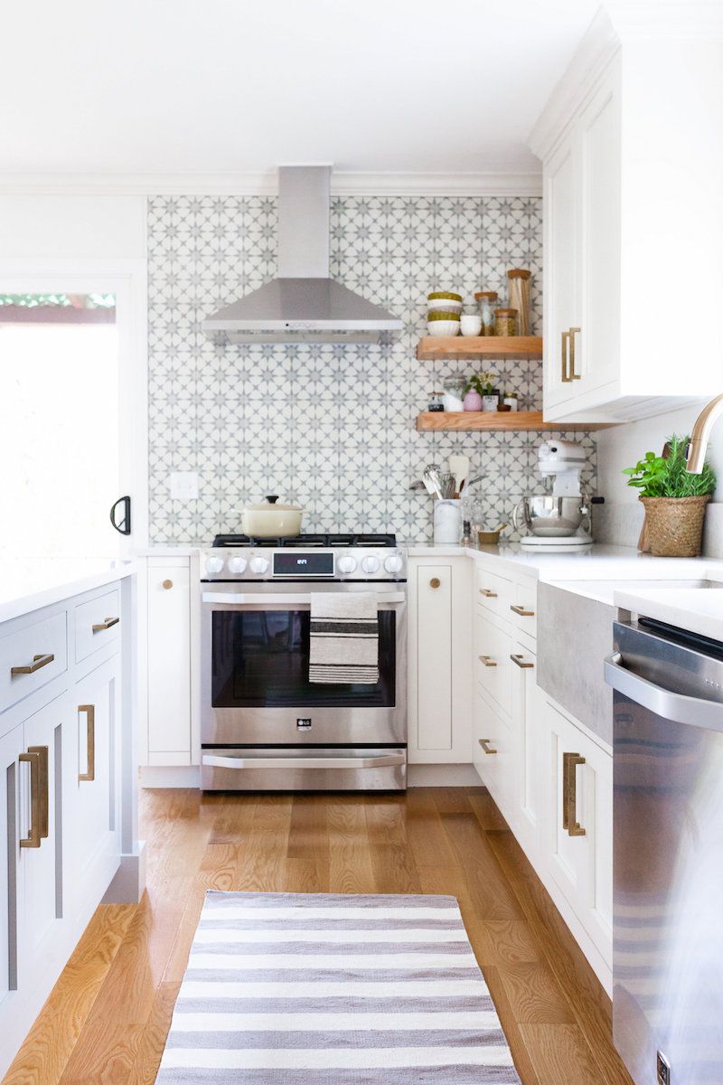 kleine grau-weiße Küche mit Holzfußboden und Edelstahlgeräten