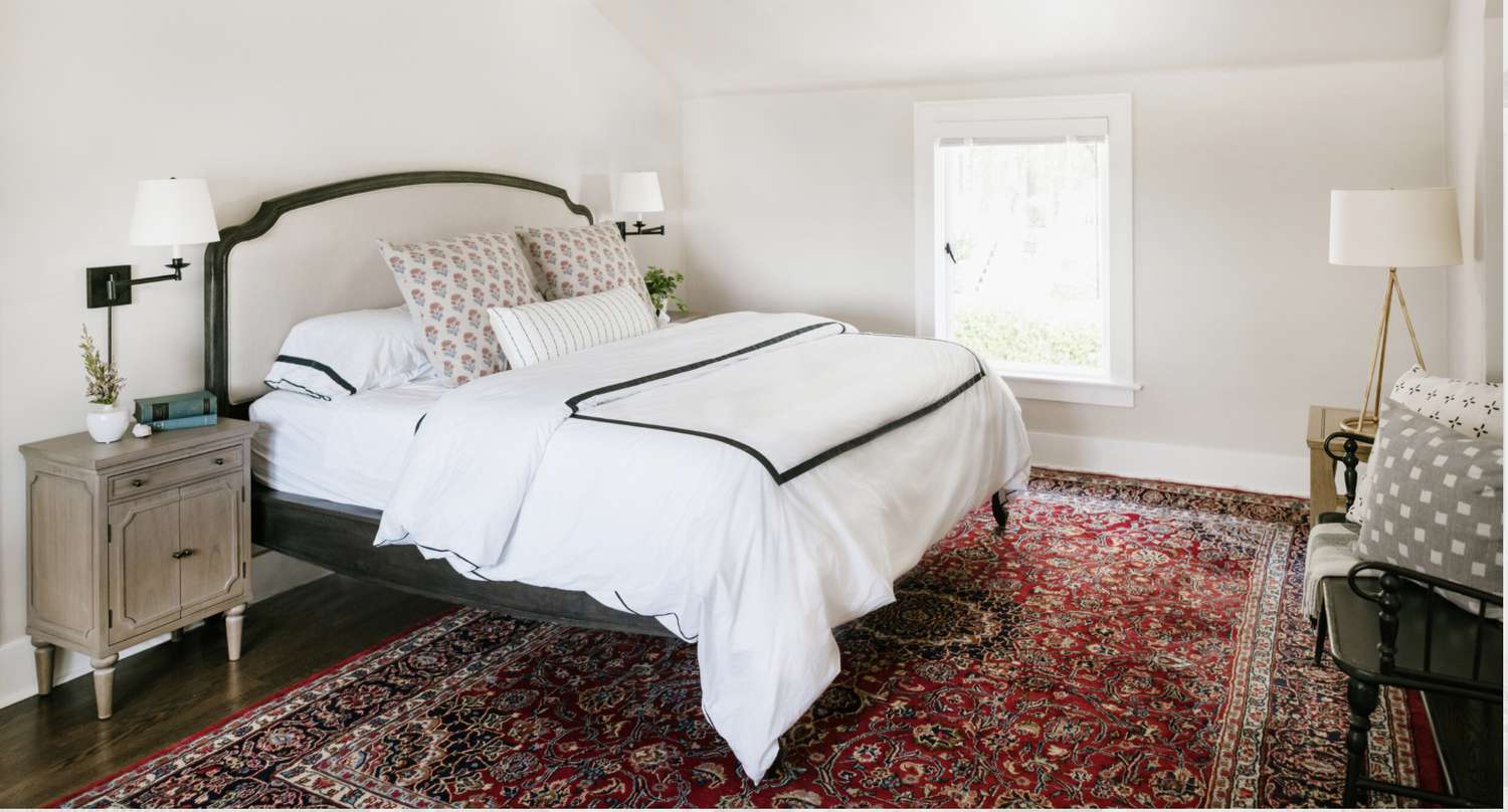 bed room with giant red paisley rug, white color scheme throughout
