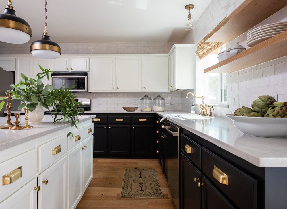 Armoires de cuisine noires et blanches avec carrelage blanc, accents de bois et quincaillerie métallique