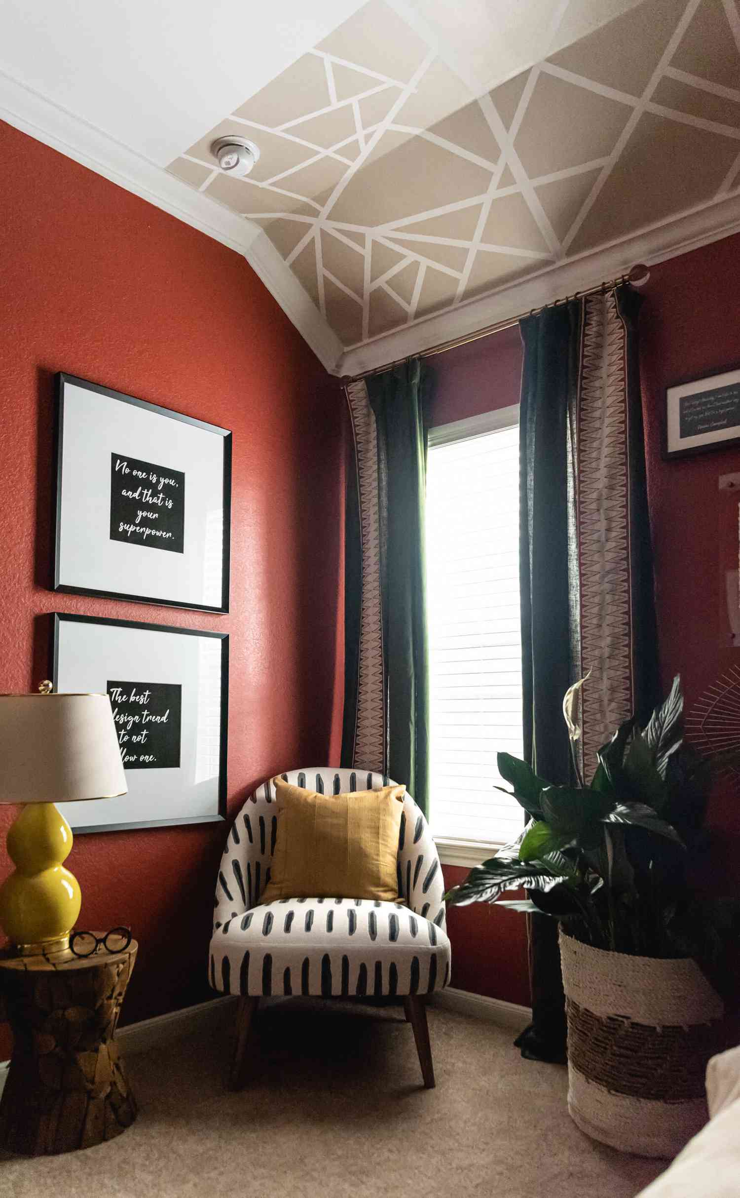 red bedroom with white and black pattern chair, red walls, mural on ceiling
