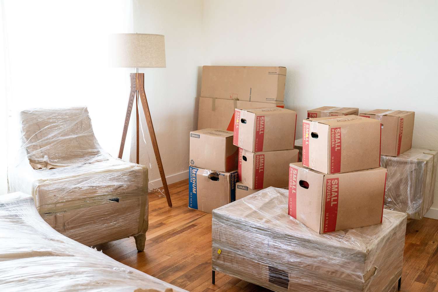 Umzugskartons und verpackte Möbel in lichtdurchfluteter Wohnung