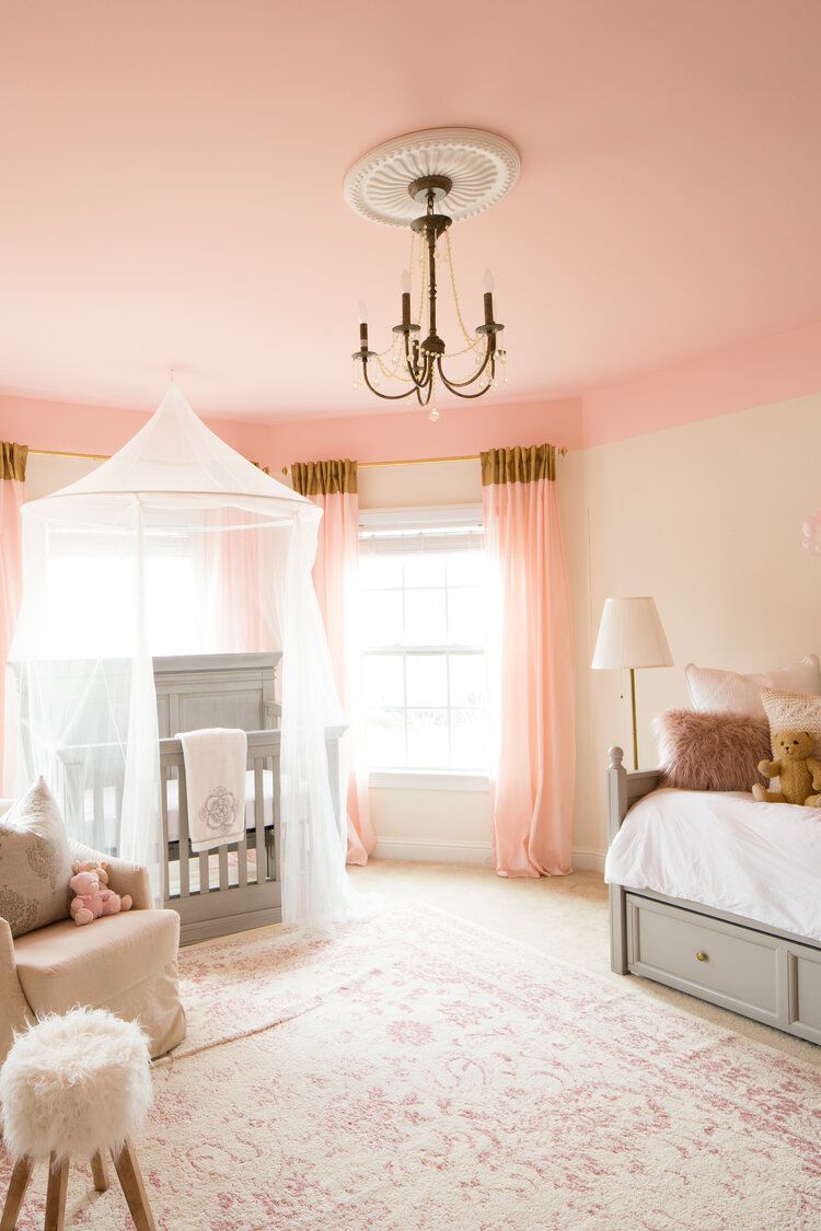 cuarto de niños rosa y gris con lámpara de araña dorada