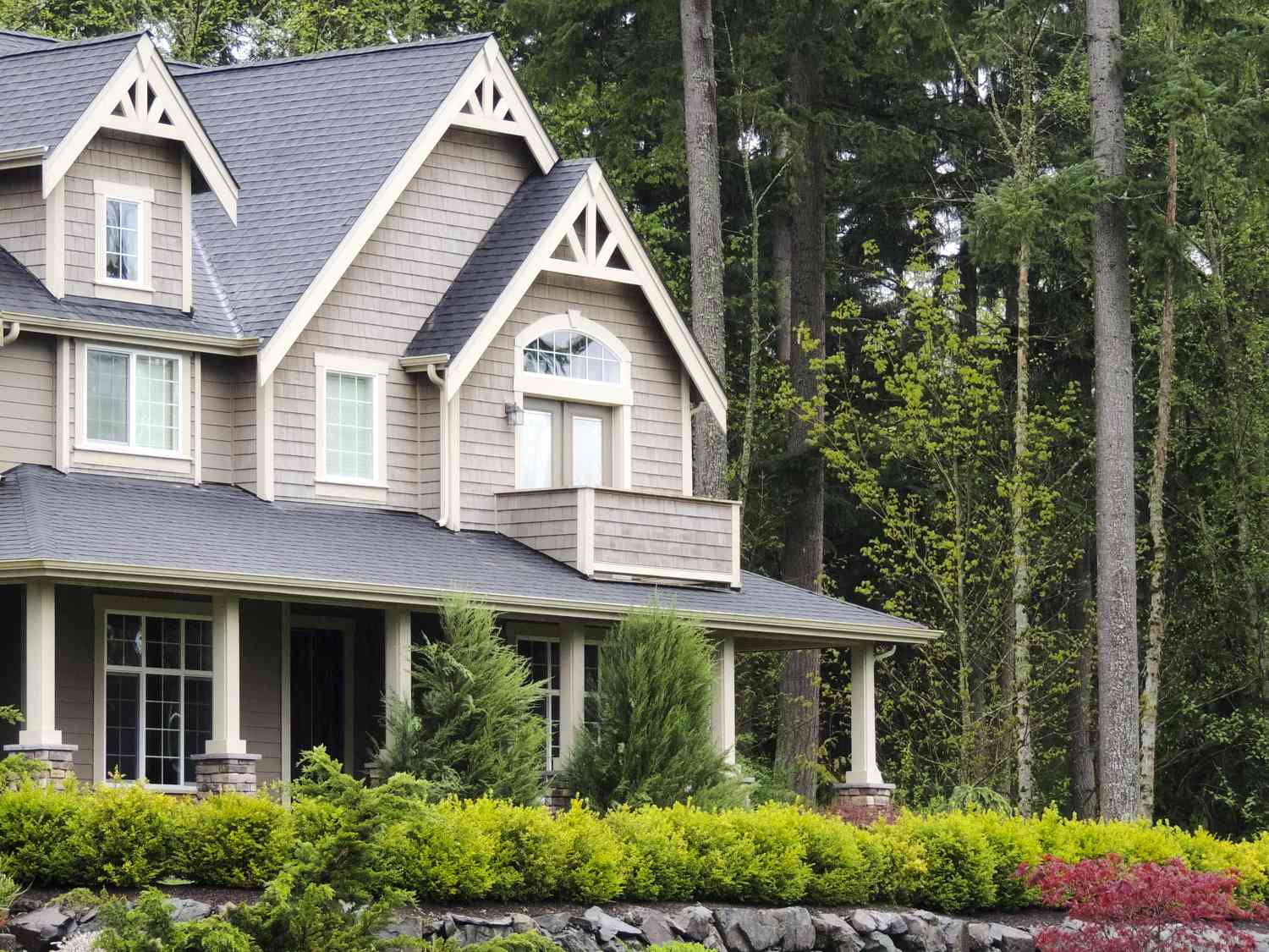 a modern home with gray exterior, green grass and trees in front yard