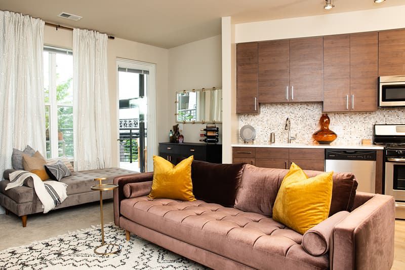 Un petit salon avec des meubles disposés de façon à créer deux espaces de vie devant la cuisine.
