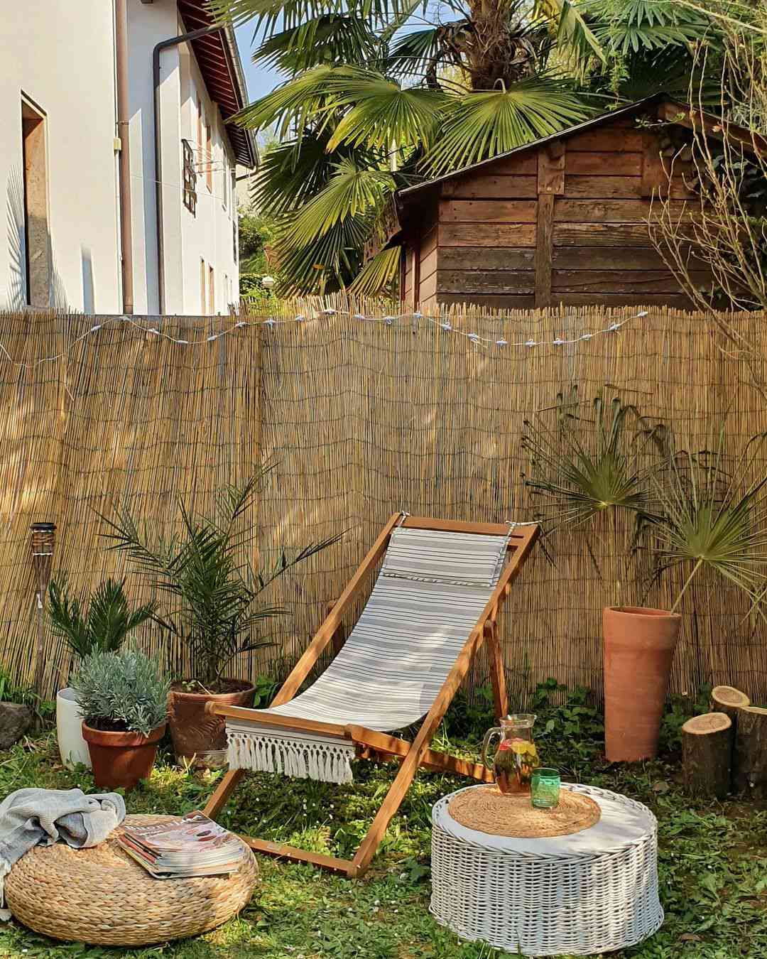 Um quintal com uma cadeira de piscina, mesas de tecido e pufe.