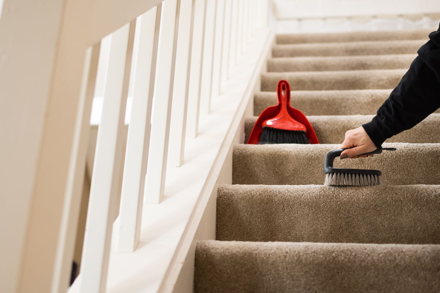 Brosse à main enlevant la saleté de l'escalier moquette avec pelle à poussière