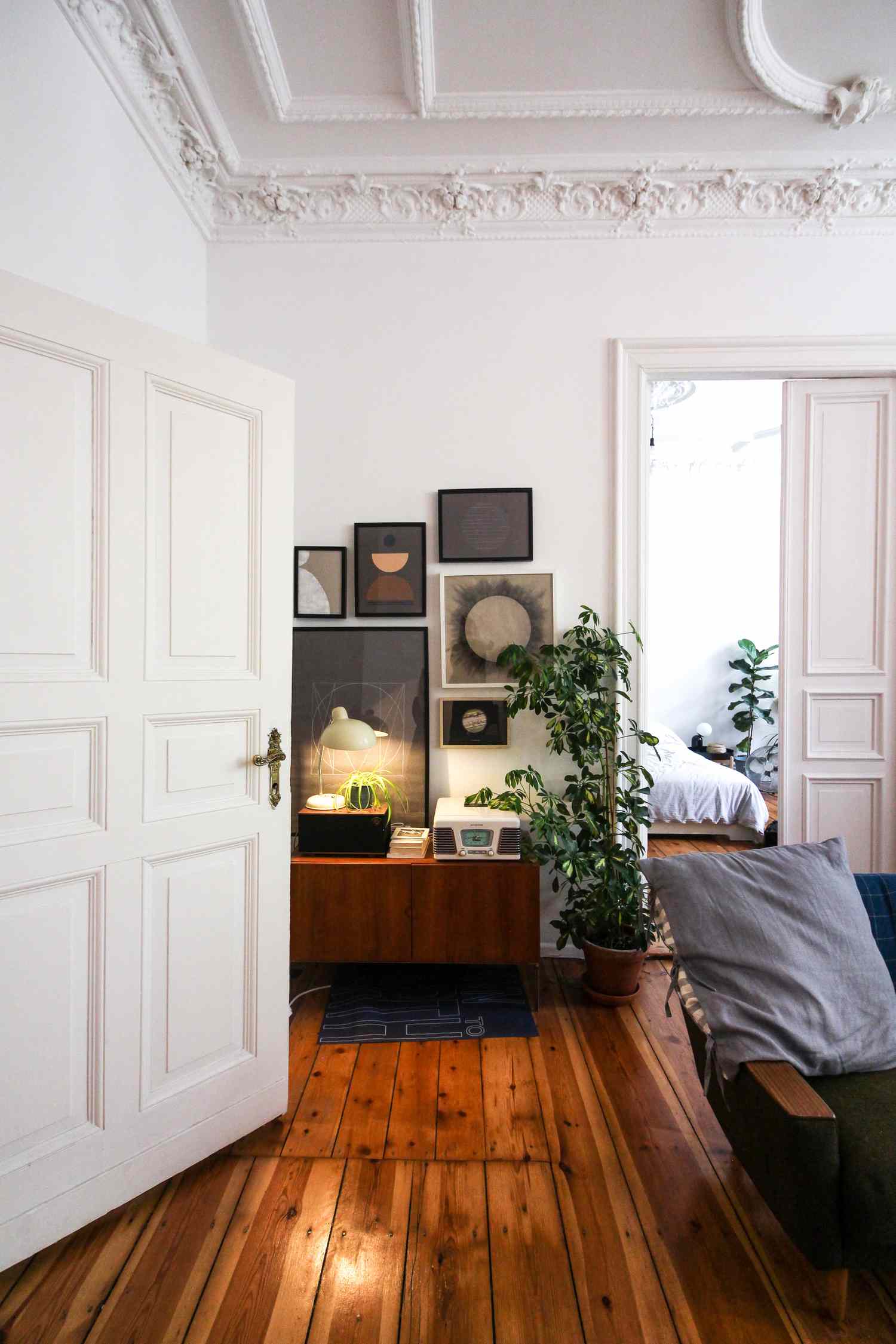 Wohnzimmer mit Kunstwerken und Holzböden gegenüber einer Schlafzimmertür