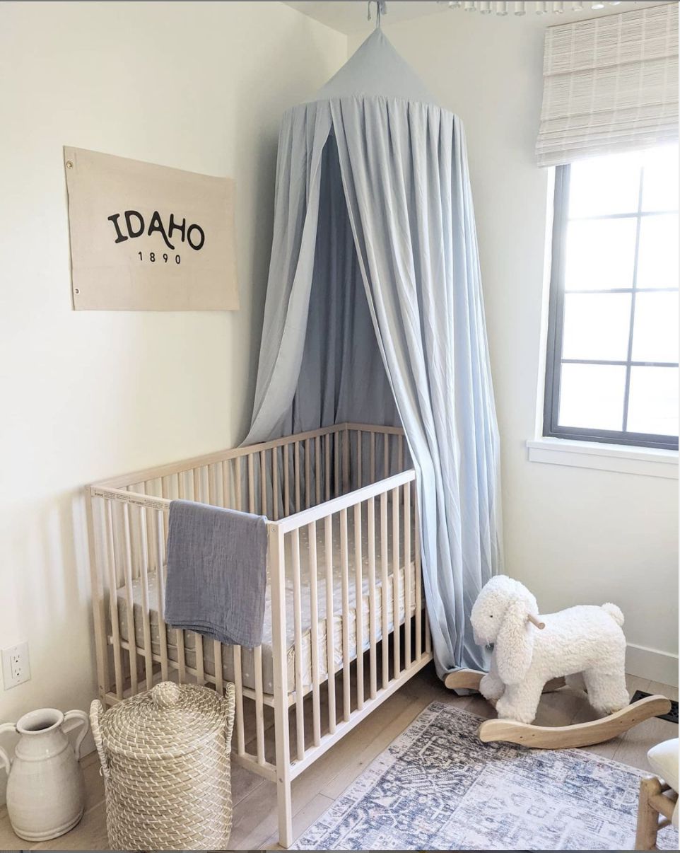 quarto de bebê com dossel azul claro e decoração off white