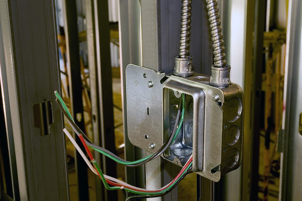Ein Elektrokasten und ein Leerrohr werden in einer Metallrahmenwand installiert.