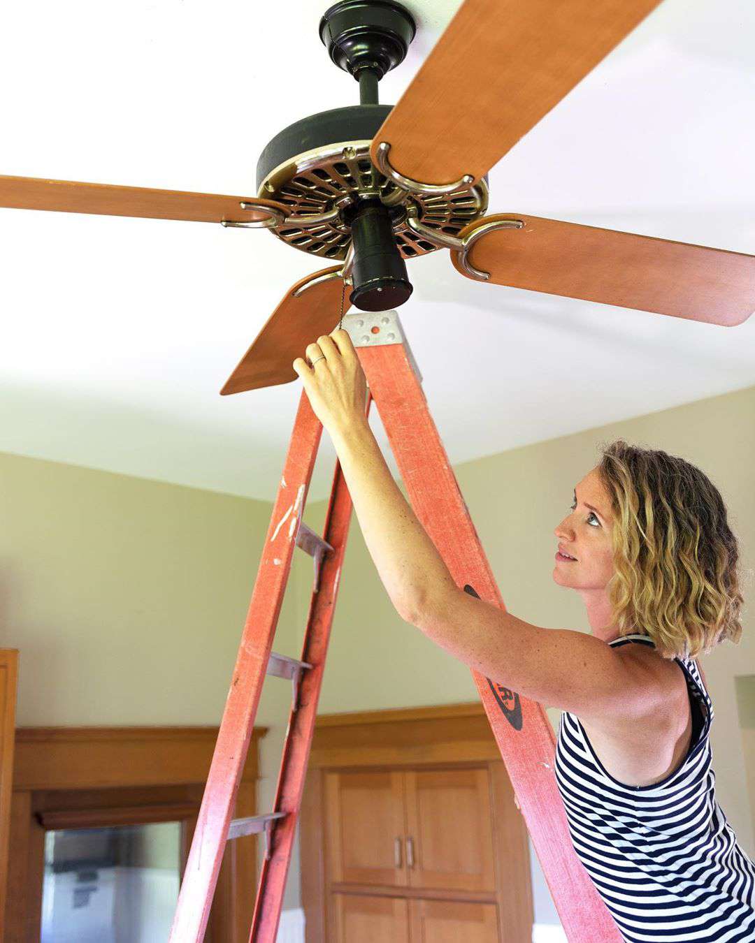 Mujer ajustando ventilador de techo