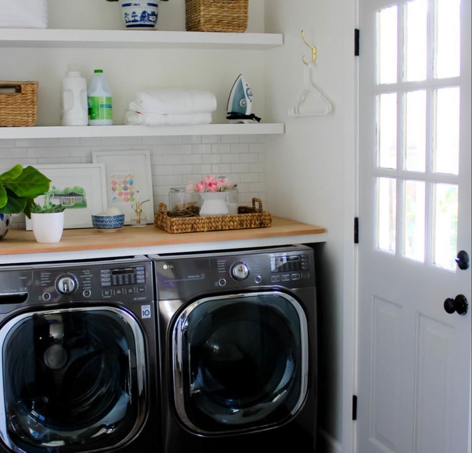 Cuarto de lavado con estanterías abiertas y electrodomésticos negros.