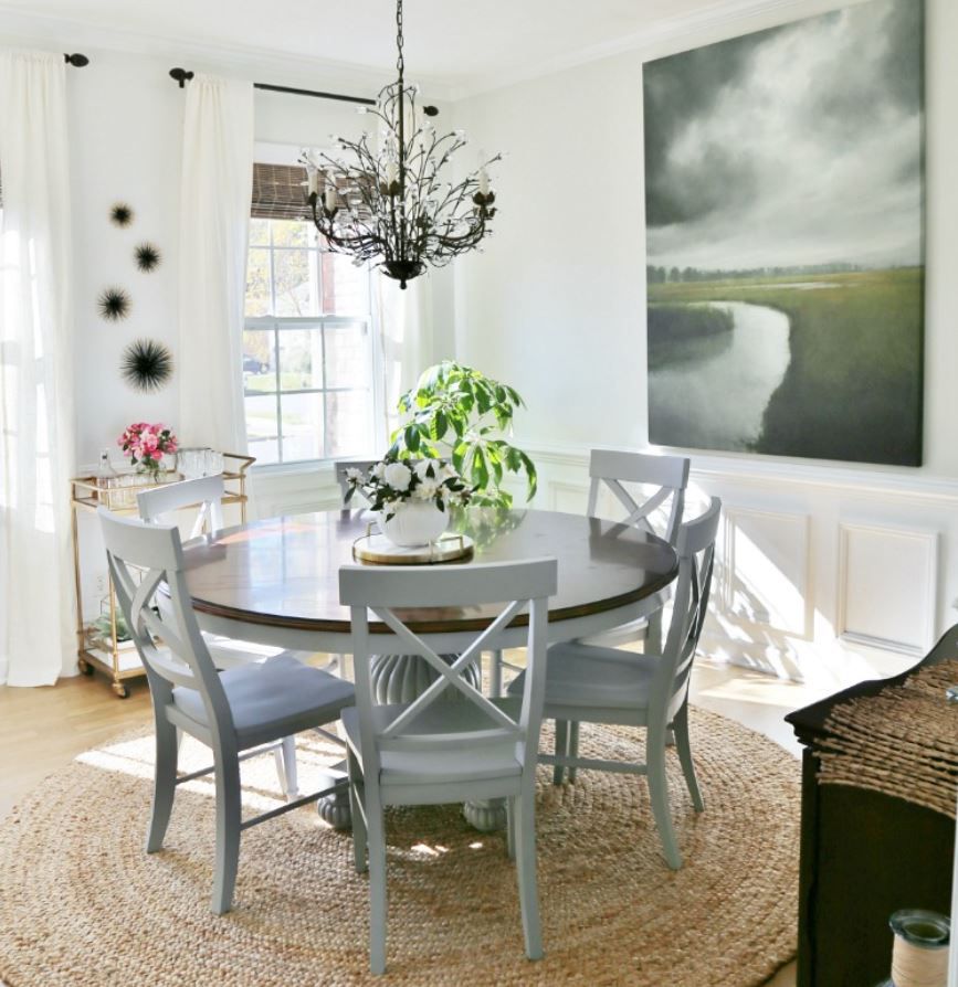 Sala de jantar de inspiração litorânea com paredes brancas e mesa redonda de fazenda.