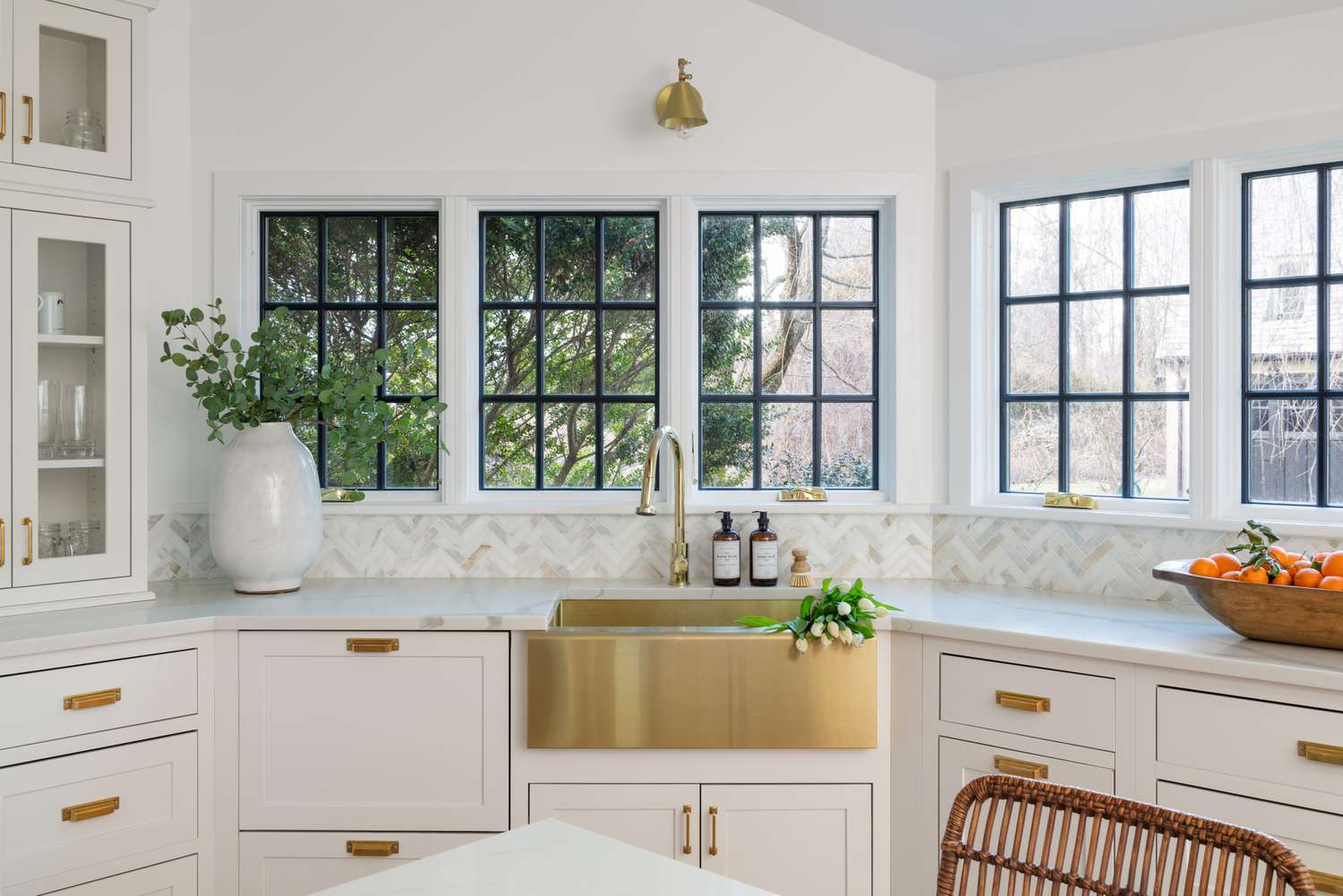 Die weiße Küche im Haus von Erin Coren hat ein goldenes Waschbecken, weiße Schränke und Fenster mit schwarzen Rahmen