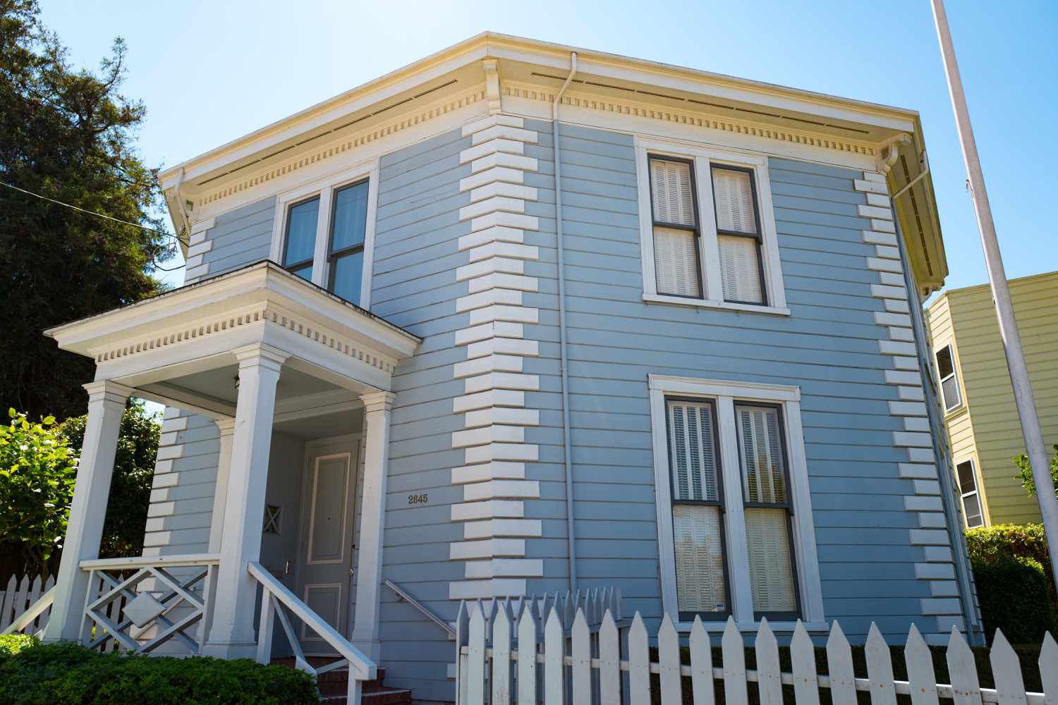 casa de dois andares com laterais azuis e acabamento branco, com quinas brancas, varanda quadrada em um dos oito lados