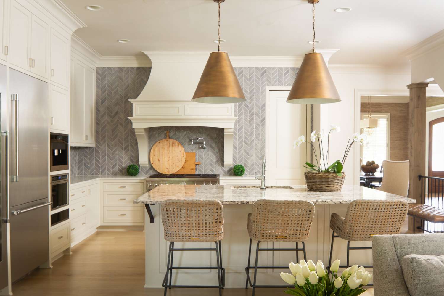 Uma cozinha de transição com azulejos de mármore em espinha de peixe e detalhes em ouro e prata