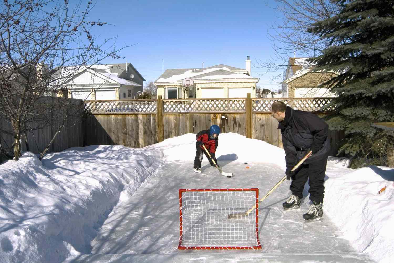 Padre e hijo jugando al hockey en el patio trasero, Winnipeg, Manitoba