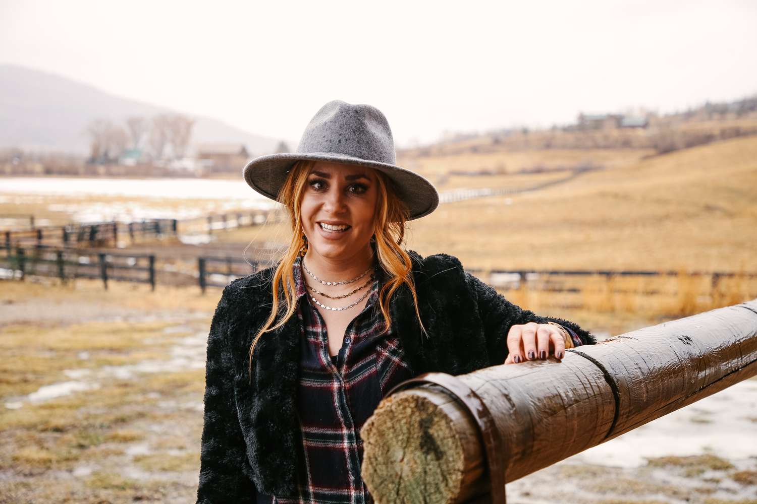 Katie Burnett posa junto a una valla de madera en una granja