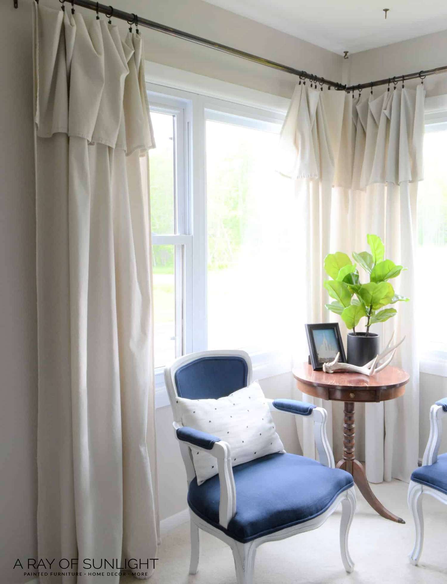 A living room with drop cloth curtains