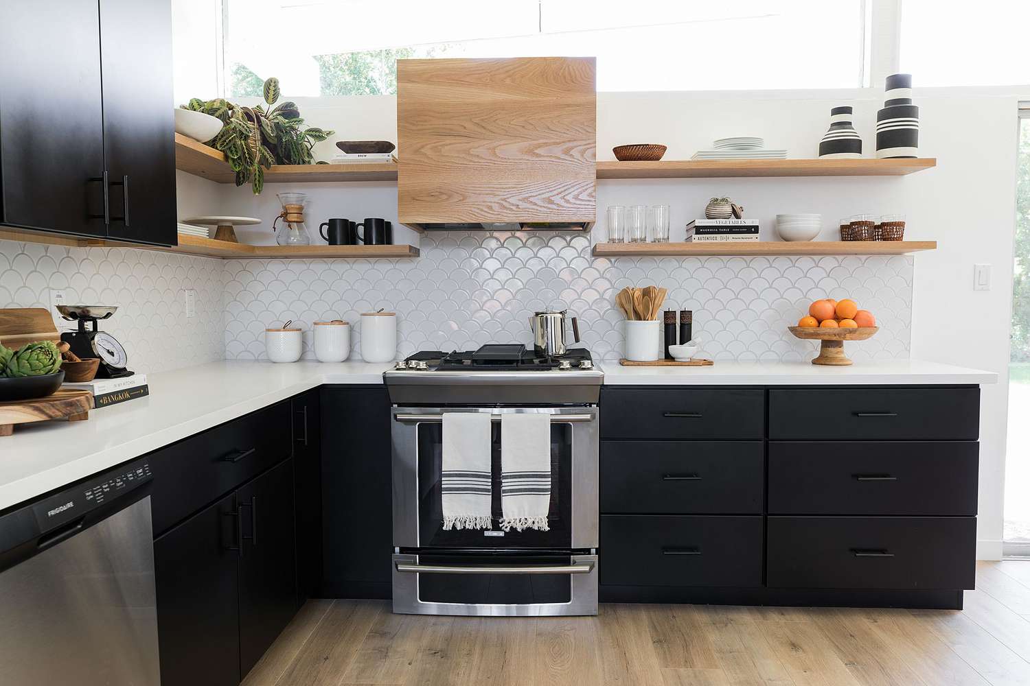 Elegante cocina moderna con armarios negros y estantes de madera al aire libre