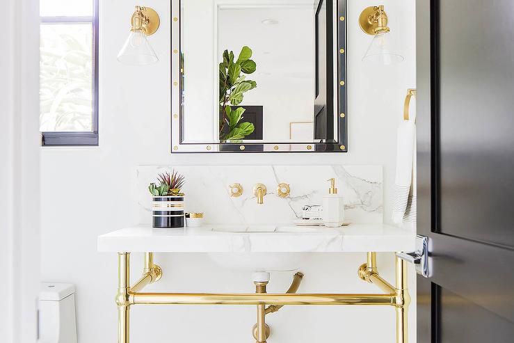 white marble backsplash and sink in a bathroom with gold fixtures