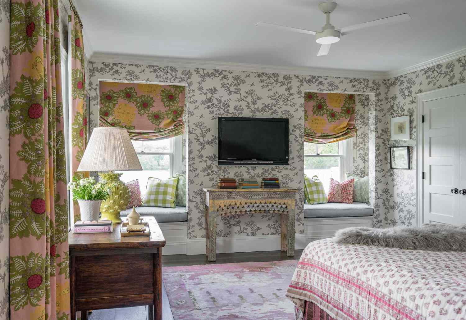 Blumentapete schmückt die Wände dieses Schlafzimmer im Landhausstil mit geblümten Fensterdekorationen, frischen Blumen und einer geblümten Bettdecke