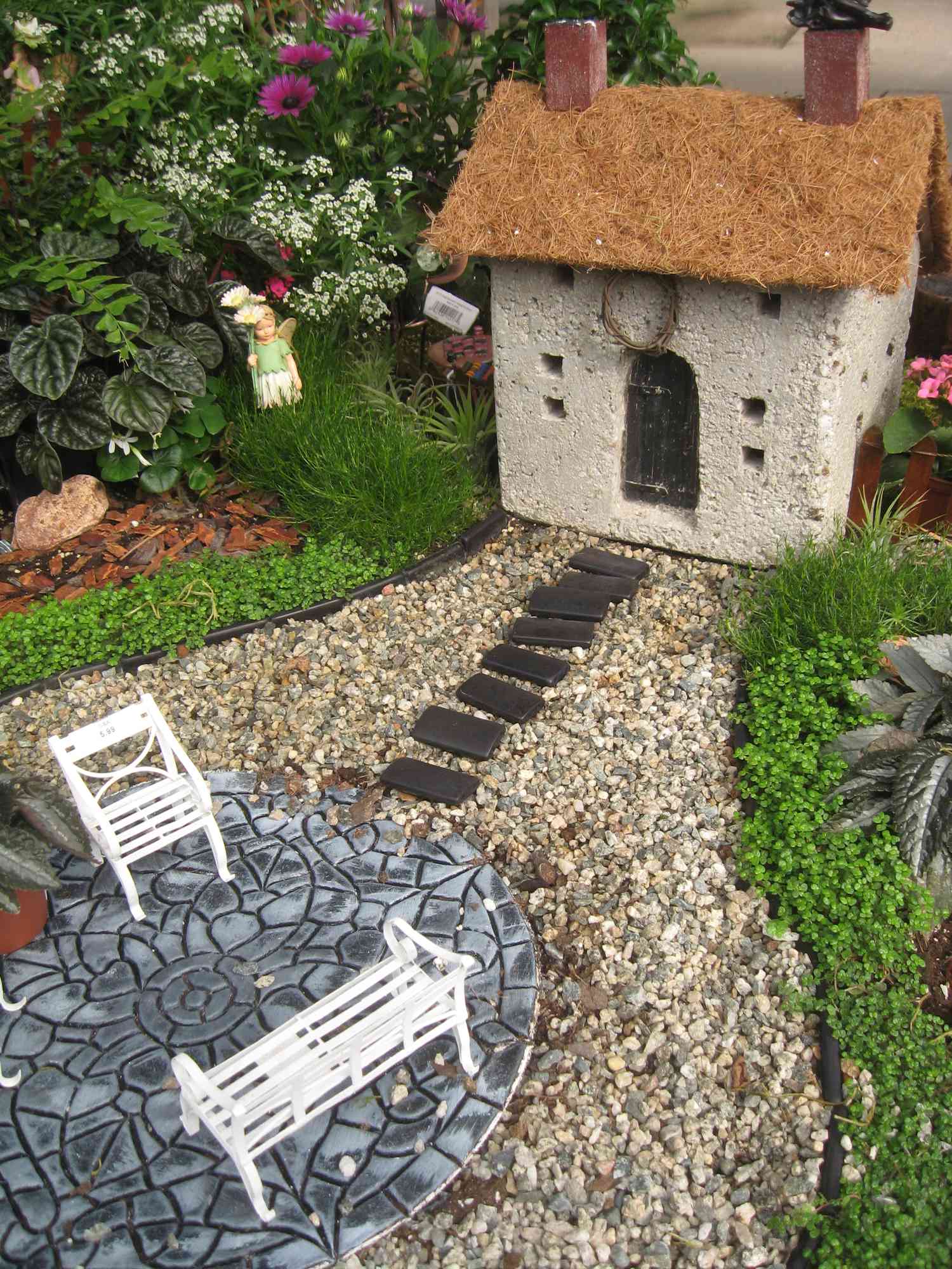 Casa e móveis em miniatura em um jardim de fadas.